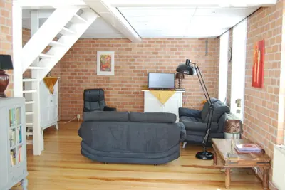 a living room with a couch and a brick wall at Bed&Brood De StraVerdonk in Graft