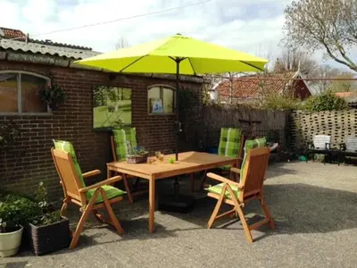 a wooden table and chairs with a yellow umbrella at Bed&Brood De StraVerdonk in Graft