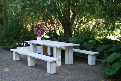 a white picnic table and two benches with flowers on it at Bed&Brood De StraVerdonk in Graft