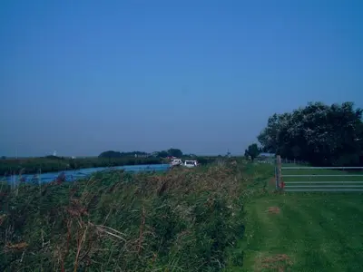 a grassy field with a river and a fence at Ferienhaus Lisakowski in Warmenhuizen