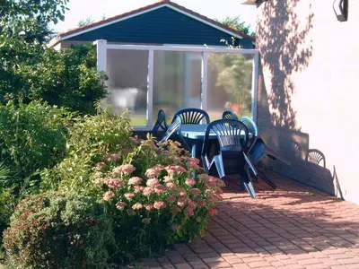 a group of chairs and a table on a porch at Ferienhaus Lisakowski in Warmenhuizen