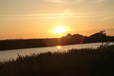 a sunset over a river with the sun setting at Ferienhaus Lisakowski in Warmenhuizen