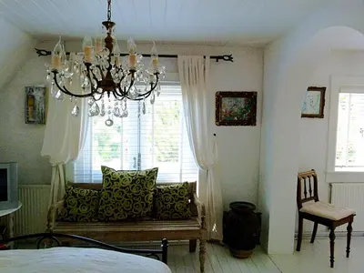 a bedroom with a chandelier and a couch in front of a window at Ons Buiten in Bergen
