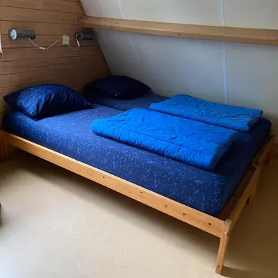 a bed in a room with blue pillows on it at Eureka Vakantiehuisjes in Schoorl