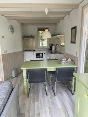 a kitchen with a green table and chairs at Eureka Vakantiehuisjes in Schoorl