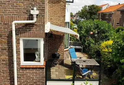 a small patio with a table and a window at Have a nice stay! - Strand Vakantiehuis Noordwijk in Noordwijk aan Zee