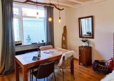 a dining room with a table and chairs and a window at Have a nice stay! - Strand Vakantiehuis Noordwijk in Noordwijk aan Zee