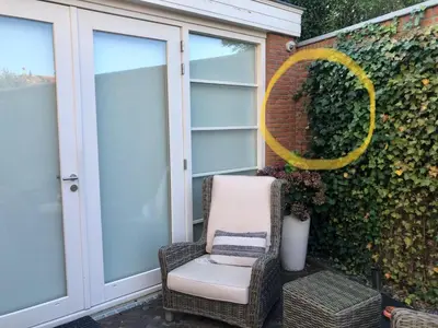 a chair sitting on a patio next to a wall at Have a nice stay! - La Casita Alta Free Parking in Noordwijk aan Zee
