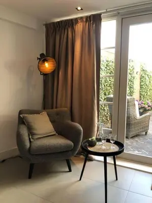 a living room with a chair and a table and a window at Have a nice stay! - La Casita Alta Free Parking in Noordwijk aan Zee
