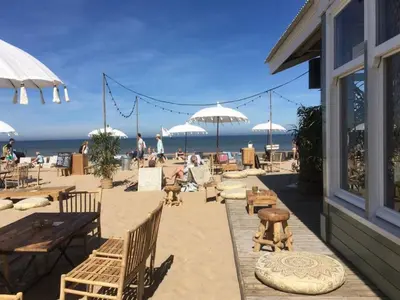 a beach with tables and chairs and umbrellas at Have a nice stay! - La Casita Alta Free Parking in Noordwijk aan Zee