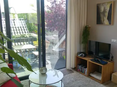 a living room with a television and a balcony at Appartementen Het Oude Atelier in Schoorl