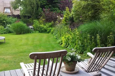 two wooden chairs sitting on a deck in a garden at Appartementen Het Oude Atelier in Schoorl