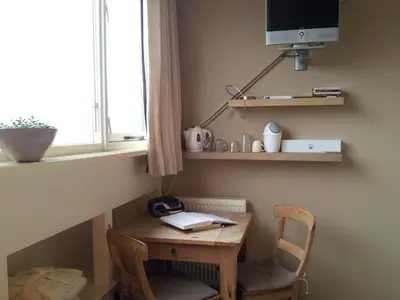 a small wooden table with a chair and a window at Appartementen Het Oude Atelier in Schoorl