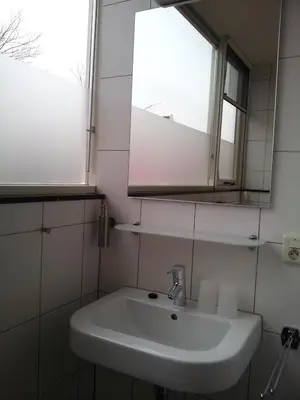 a white sink in a bathroom with a window at Appartementen Het Oude Atelier in Schoorl