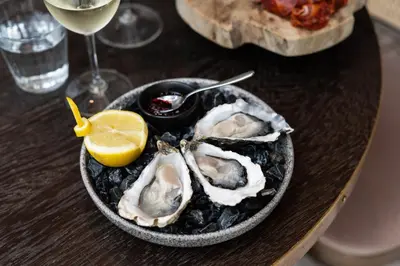 a bowl of oysters on a table with a glass of wine at Ysbrantsz Boutique Hotel in Hoorn