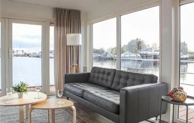 a living room with a couch and large windows at Cozy Ship In Aalsmeer With Wifi in Aalsmeer