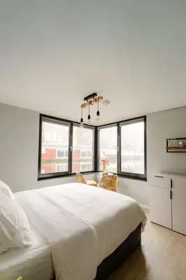 a white bedroom with a large bed and windows at 2 Houseboat Suites Amsterdam Prinsengracht in Amsterdam
