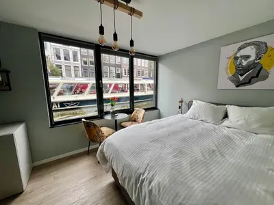 a bedroom with a large bed and two windows at 2 Houseboat Suites Amsterdam Prinsengracht in Amsterdam