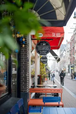 a restaurant with two benches and a sign on a building at 2 Houseboat Suites Amsterdam Prinsengracht in Amsterdam