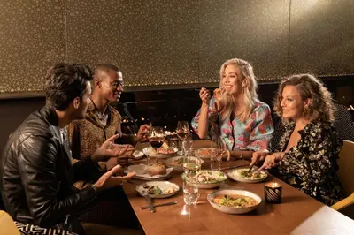 a group of people sitting around a table eating food at art'otel amsterdam, Powered by Radisson Hotels in Amsterdam
