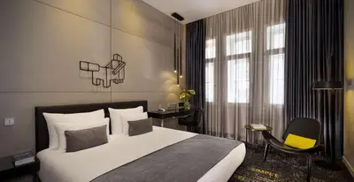a bedroom with a large bed and a chair at art'otel amsterdam, Powered by Radisson Hotels in Amsterdam