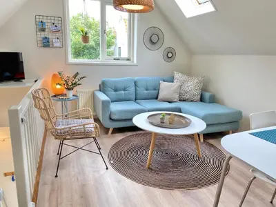 a living room with a blue couch and a table at Zandvoort Central Apartment in Zandvoort