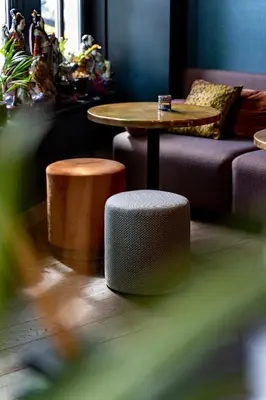 a living room with a table and a couch and stool at Hotel Mai Amsterdam in Amsterdam