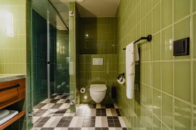 a green tiled bathroom with a toilet and a shower at Hotel Mai Amsterdam in Amsterdam