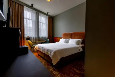 a hotel room with a bed and a chair and window at Hotel Mai Amsterdam in Amsterdam
