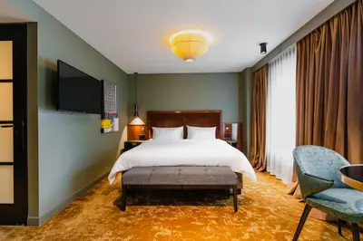 a bedroom with a bed and a tv and chairs at Hotel Mai Amsterdam in Amsterdam