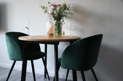 a table with two green chairs and a vase of flowers at Greenstay in Amsterdam