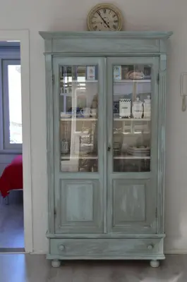a green cabinet with dishes in it with a clock at Sea in Egmond aan Zee