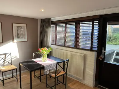a dining room with a table and chairs and a window at In The Heart of Zandvoort in Zandvoort