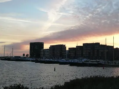 a group of boats docked in a marina at sunset at Private Lodge on Houseboat Amsterdam in Amsterdam