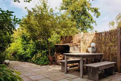 a patio with a table and a bench and a fence at Zee-en-Zo Noordwijk in Noordwijk