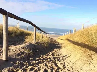 a sandy beach with a wooden fence and the ocean at Zee-en-Zo Noordwijk in Noordwijk