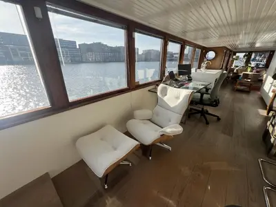 a room with a desk and chairs and windows at Stunning boat with a view in Amsterdam