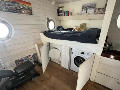 a dog laying on a bed in a tiny house at Stunning boat with a view in Amsterdam