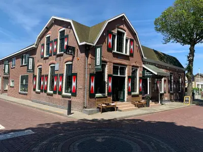 a large brick building with red shutters on a street at Boutique Hotel Herberg Binnen in Egmond-Binnen