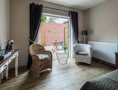 a bedroom with a bed and two chairs and a window at Boutique Hotel Herberg Binnen in Egmond-Binnen