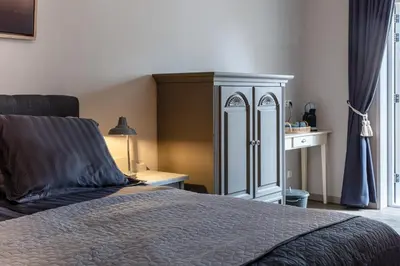 a bedroom with a large bed and a cabinet at Boutique Hotel Herberg Binnen in Egmond-Binnen