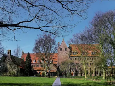 a large brick building with trees in front of it at Boutique Hotel Herberg Binnen in Egmond-Binnen