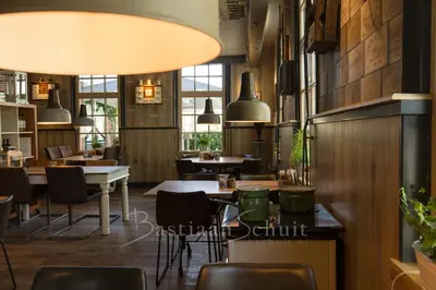a restaurant with wooden walls and tables and chairs at Boutique Hotel Herberg Binnen in Egmond-Binnen