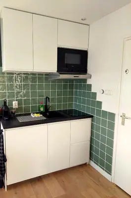 a kitchen with white cabinets and a green tiled wall at City & Nature-Amsterdam NextDoor Free parking 8 person 2 kitchens in Landsmeer