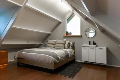 a bedroom with a bed in a loft with a window at City & Nature-Amsterdam NextDoor Free parking 8 person 2 kitchens in Landsmeer