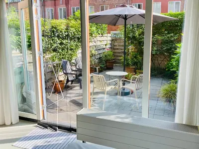 a patio with a table and an umbrella at Private studio, patio garden and free car parking in Amsterdam