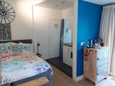 a bedroom with a bed and a blue wall at Studio Pipper in Zandvoort