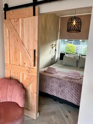 a bedroom with a sliding barn door with a bed at Amsterdam Beach Apartment 34, Private Garden in Zandvoort
