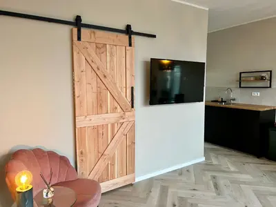 a sliding barn door in a room with a table at Amsterdam Beach Apartment 34, Private Garden in Zandvoort