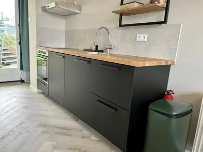a kitchen with a sink and a counter with a trash can at Amsterdam Beach Apartment 34, Private Garden in Zandvoort